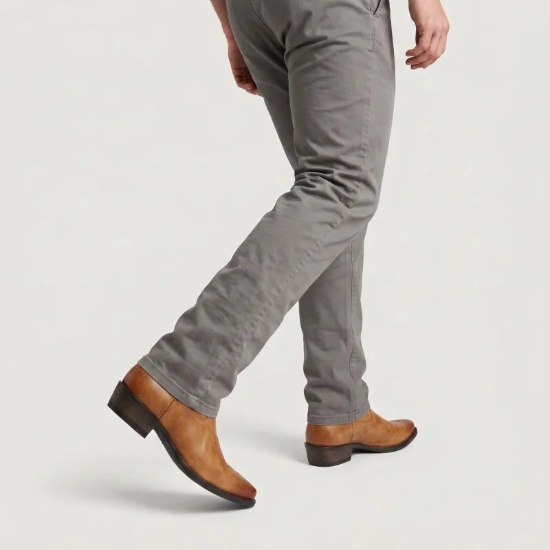 Yehaw brown vegan leather cowboy boots with a pointed toe and low heel worn by a man in grey trousers