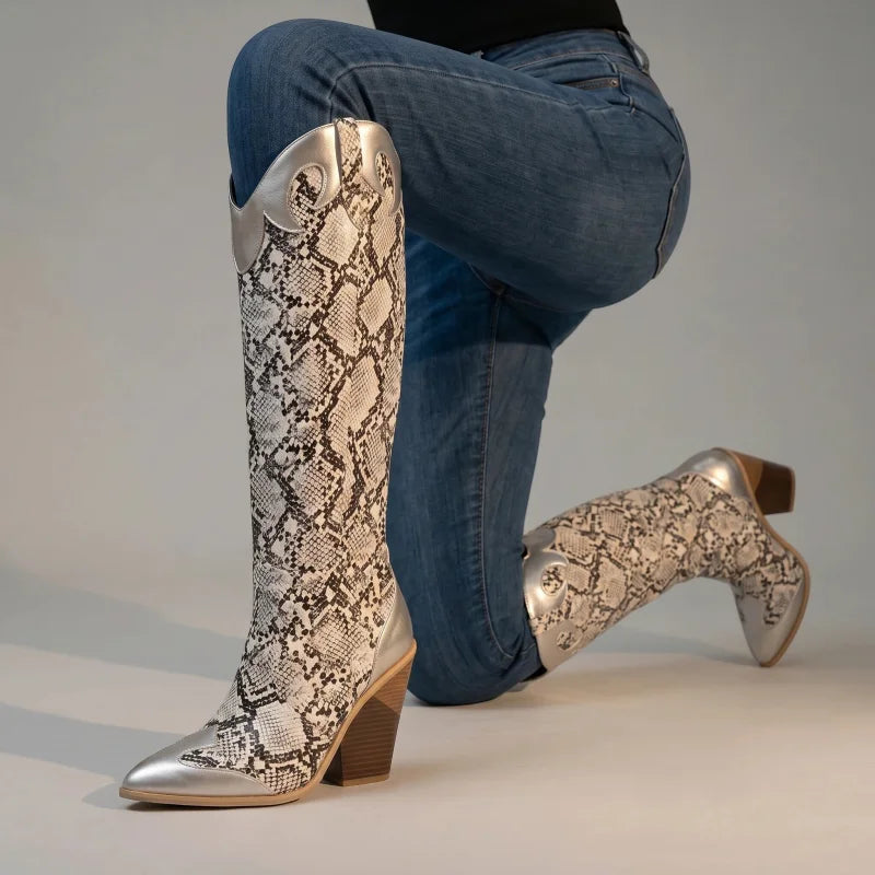 Yehaw Clementine knee-high cowboy boots in silver and snakeskin print vegan leather with a pointed toe and block heel.