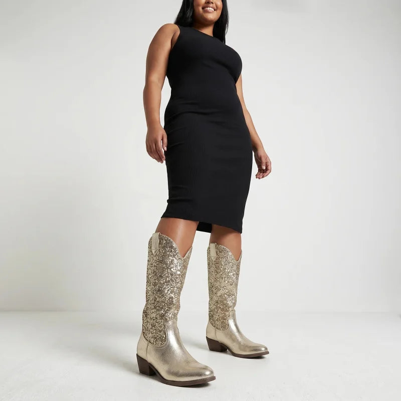 Model wearing Yehaw gold glitter mid-calf vegan microfibre cowgirl boots with a black dress