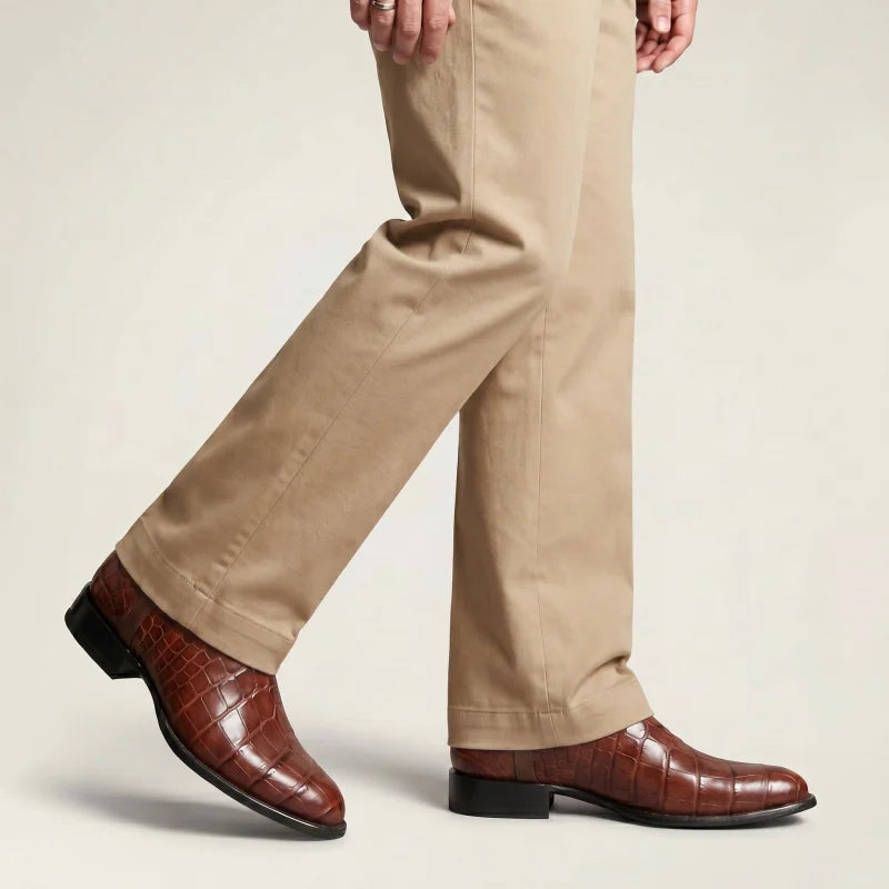 Yehaw men's brown vegan leather cowboy boots with a crocodile-embossed texture and round toe, worn with beige trousers.