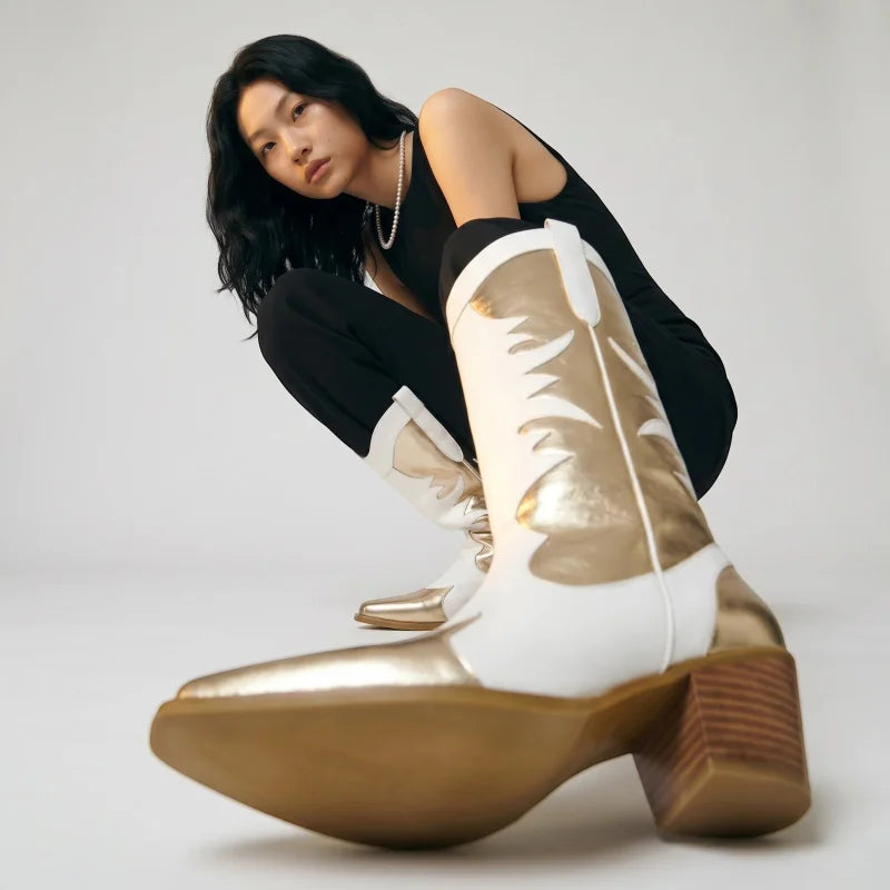 Model crouching wearing Yehaw white and gold vegan leather mid-calf cowgirl boots with a round toe and block heel.