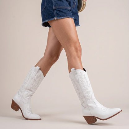 Yehaw white vegan leather mid-calf cowgirl boots with pointed toe and western stitching worn by a woman