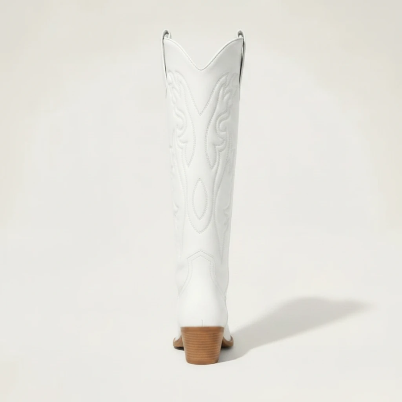 Model wearing Yehaw white vegan leather knee-high cowgirl boots with a pointed toe and medium block heel