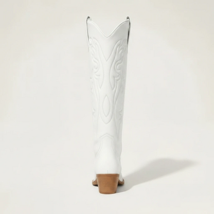 Model wearing Yehaw white vegan leather knee-high cowgirl boots with a pointed toe and medium block heel