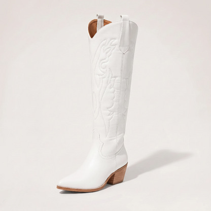 Model wearing Yehaw white vegan leather knee-high cowgirl boots with a pointed toe and medium block heel