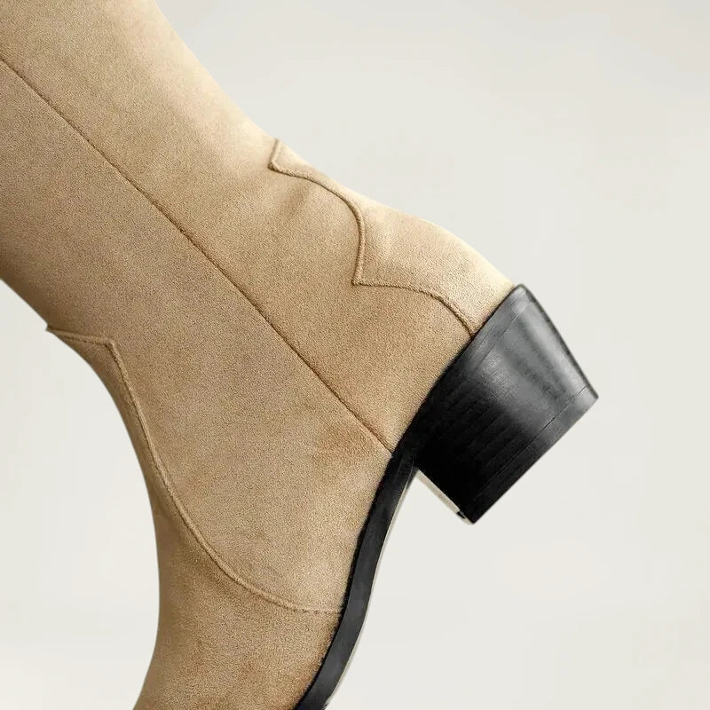 Yehaw beige vegan suede knee-high cowgirl boots with a pointed toe and side zip worn by a woman in denim shorts
