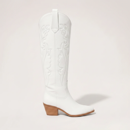 Model wearing Yehaw white vegan leather knee-high cowgirl boots with a pointed toe and medium block heel