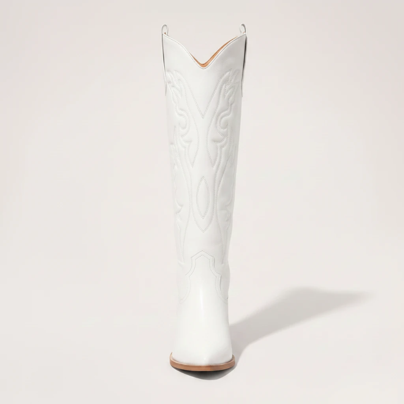 Model wearing Yehaw white vegan leather knee-high cowgirl boots with a pointed toe and medium block heel