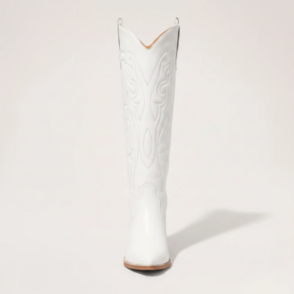 Model wearing Yehaw white vegan leather knee-high cowgirl boots with a pointed toe and medium block heel