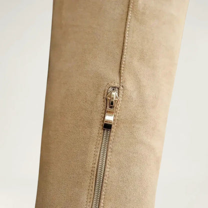 Yehaw beige vegan suede knee-high cowgirl boots with a pointed toe and side zip worn by a woman in denim shorts
