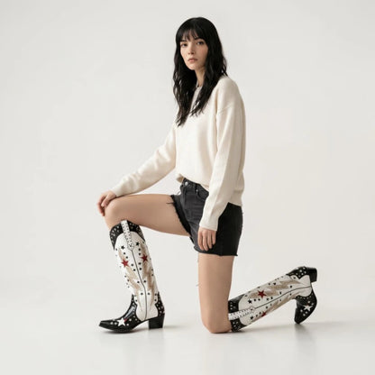 Model wearing Yehaw AMANDA black and white vegan leather cowgirl boots with star and lightning bolt embroidery.