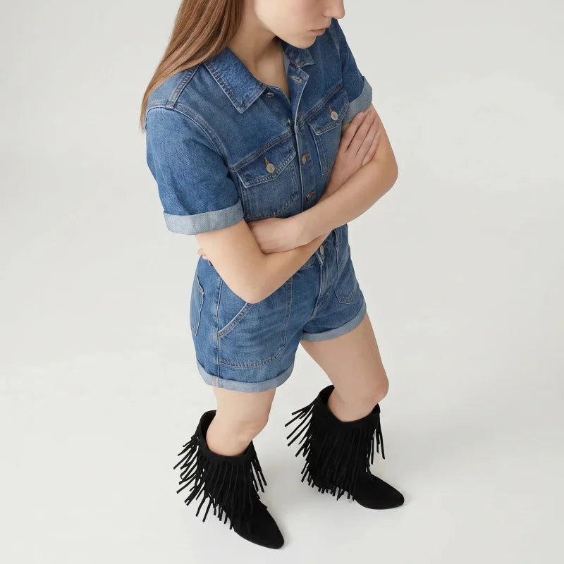 Yehaw black vegan suede mid-calf cowboy boots with fringe detail worn by a woman in a denim romper