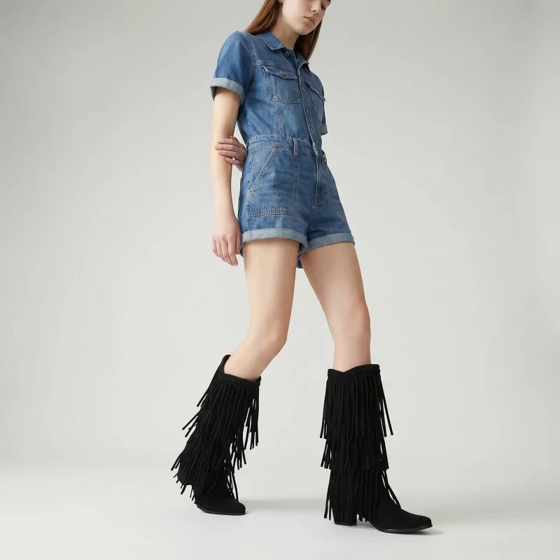 Yehaw black vegan suede mid-calf cowgirl boots with fringe detail worn by a model in a denim romper
