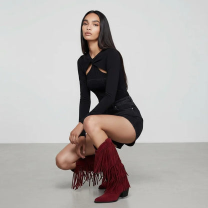 Model wearing Yehaw red vegan suede mid-calf cowgirl boots with fringe detail and pointed toe in a studio setting.
