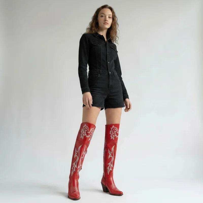 Model wearing Yehaw red knee-high vegan leather cowgirl boots with white western stitching and a pointed toe