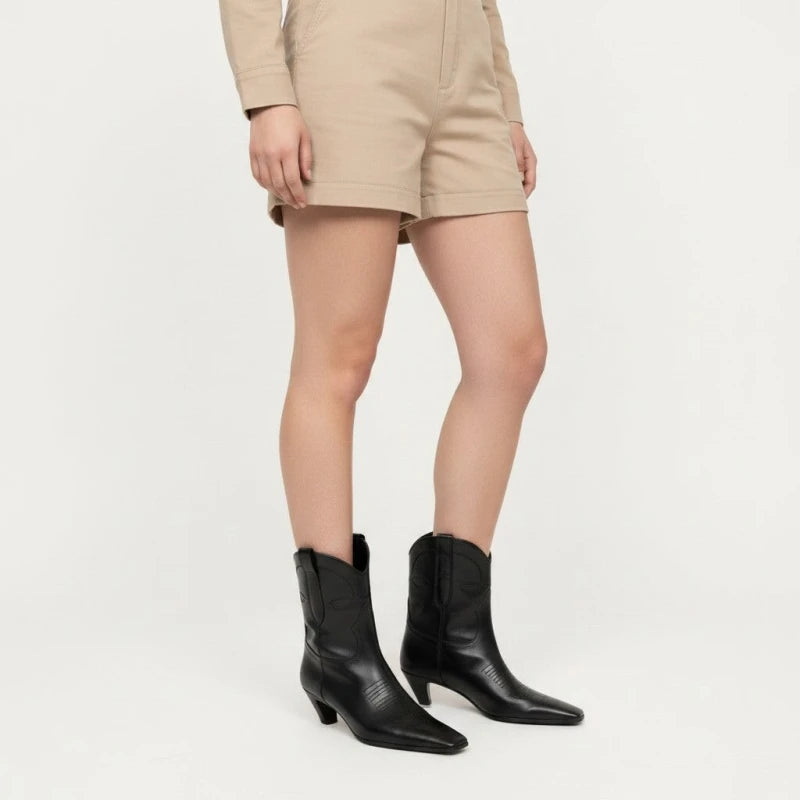 Yehaw BERTA black vegan leather ankle cowboy boots with a square toe and medium heel worn with beige shorts.