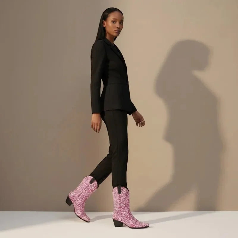 Yehaw pink vegan glitter cowgirl boots with pointed toe and medium heel, worn by a woman in a black suit.