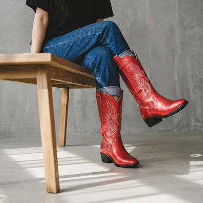 Yehaw red vegan leather mid-calf cowgirl boots with white stitching and pointed toe, worn with blue jeans.