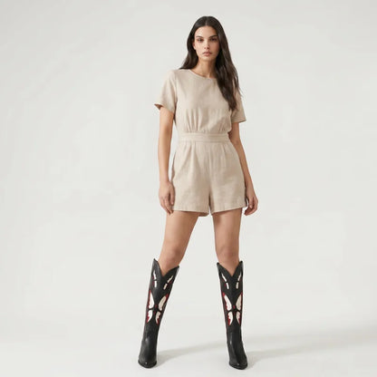 A model wearing Yehaw black vegan leather mid-calf cowgirl boots with beige butterfly embroidery and a beige romper.
