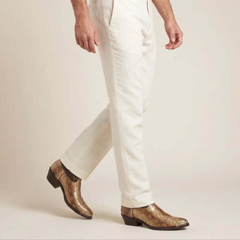 Yehaw golden brown vegan leather cowboy boots with crocodile texture worn by a man in cream trousers
