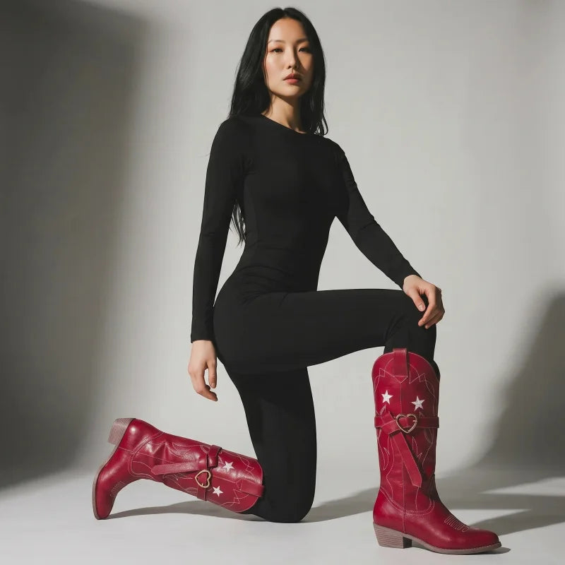 Model wearing Yehaw red vegan leather mid-calf cowgirl boots with white star embroidery and heart buckle detail.