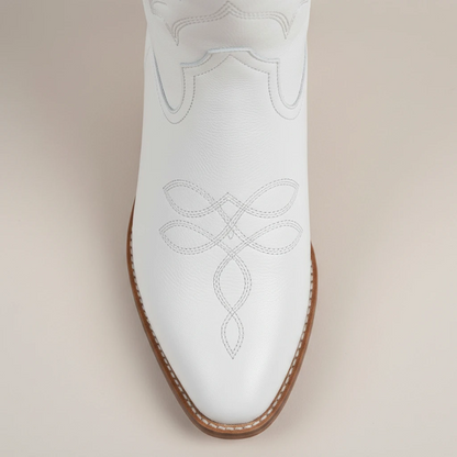 Yehaw white vegan leather mid-calf cowgirl boots with pointed toe and western stitching worn by a woman