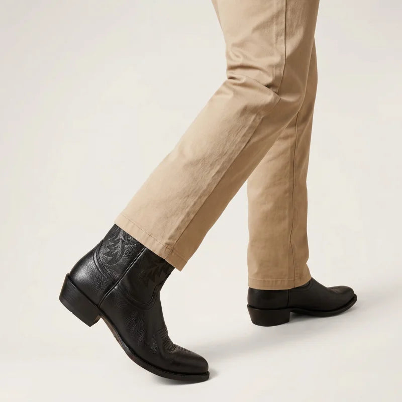 Yehaw black vegan leather cowboy boots with round toe and western stitching, worn with beige trousers.