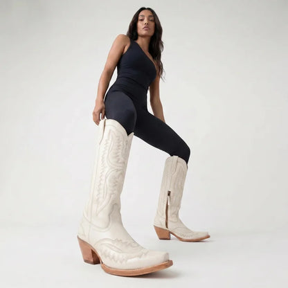 Model wearing Yehaw white knee-high vegan leather cowgirl boots with pointed toe and western stitching