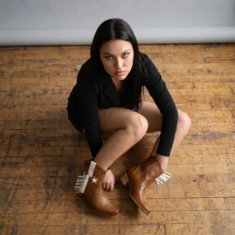 Yehaw Orlanda brown vegan leather ankle cowboy boots with white fringe and star detail worn by a woman