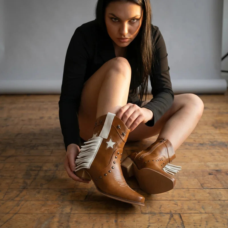 Yehaw Orlanda brown vegan leather ankle cowboy boots with white fringe, star details, and high heels on a model.