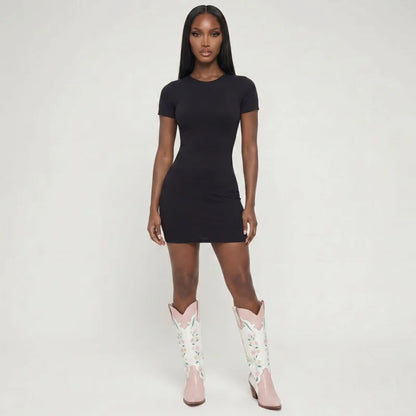 Model wearing Yehaw RIA knee-high white and pink vegan leather cowgirl boots with floral embroidery and pointed toes.